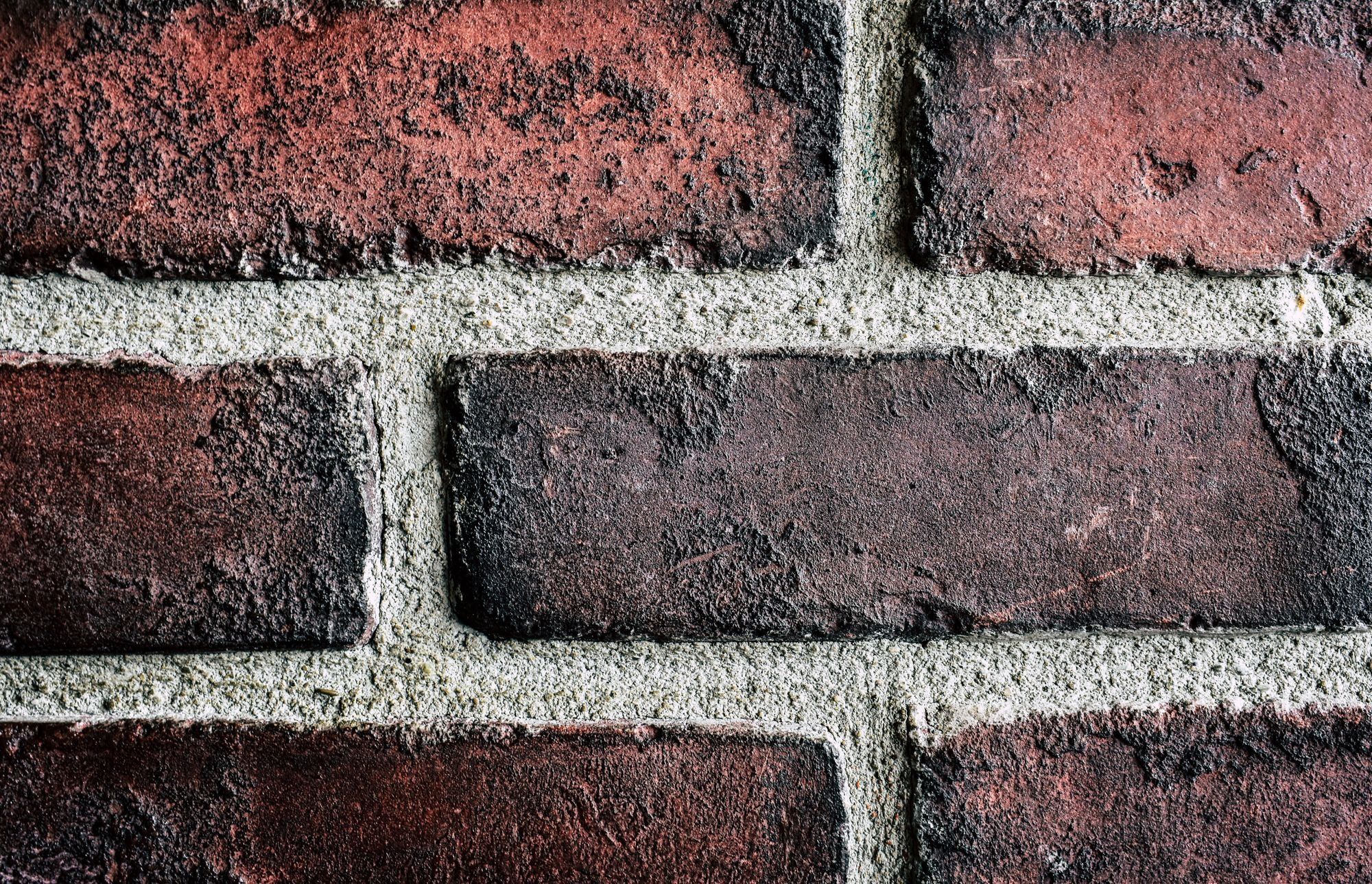 Close-up of weathered red bricks with pale grey mortar joints between them