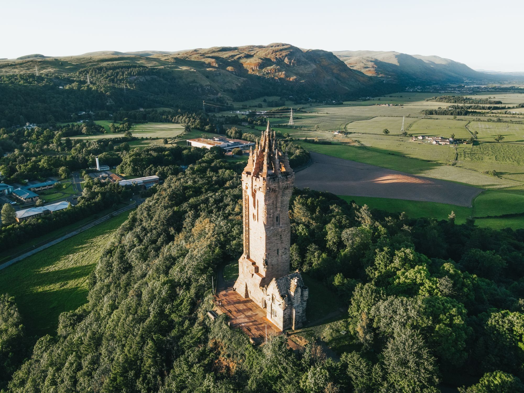 The Wallace Monument on Abbey Craig at golden hour, with the Ochil Hills rising behind